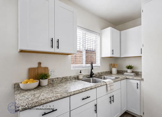 A kitchen with white cabinets and a granite countertop.