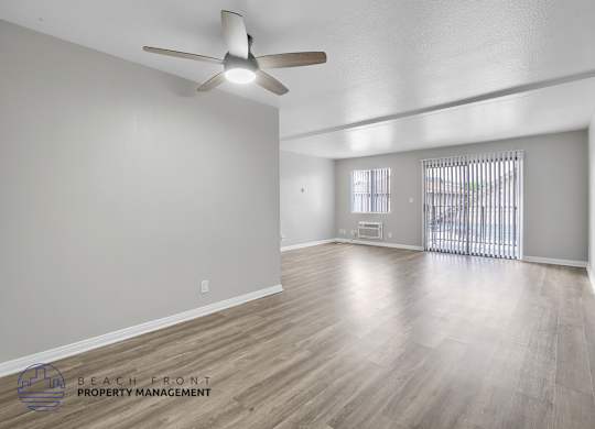 A spacious room with a ceiling fan and wooden flooring.
