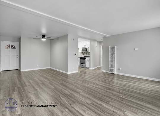 A spacious room with wooden flooring and a ceiling fan.