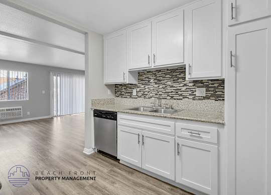 A kitchen with white cabinets and a stone backsplash.