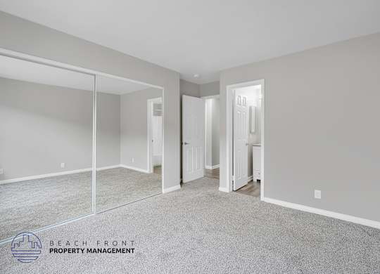 A spacious room with a carpeted floor and a mirror on the wall.