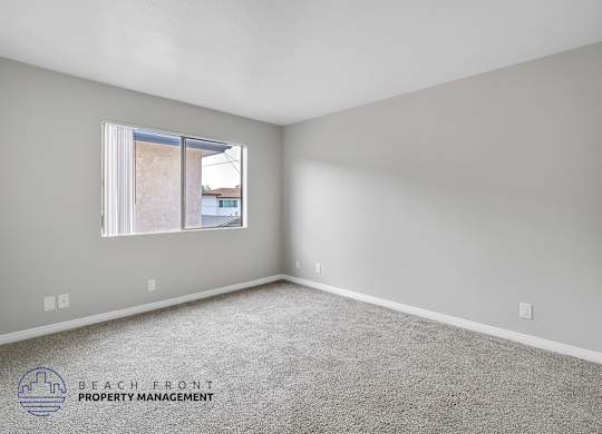 A room with a carpeted floor and a window showing a view of a building outside.