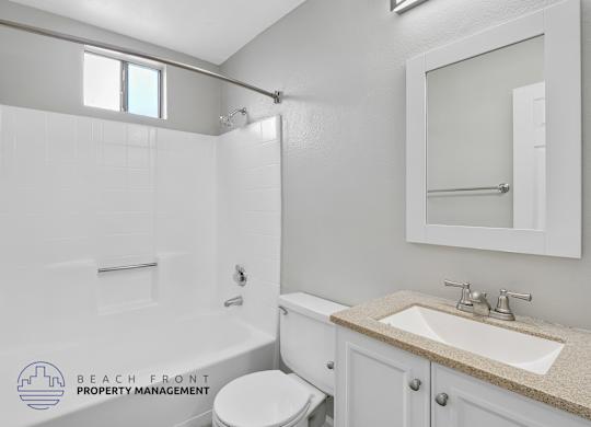 A white bathroom with a toilet, sink, and shower.