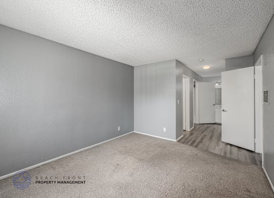 A spacious room with a carpeted floor and white walls.