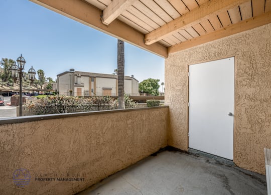 A balcony with a white door and a wall with a logo for Black Iron Property Management.