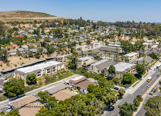 A bird's eye view of a residential area with houses, roads, and trees.