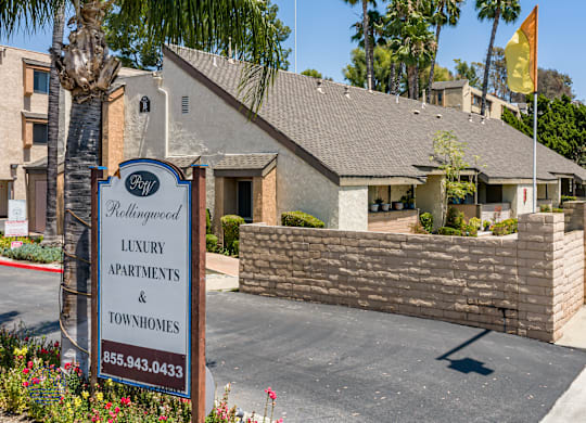 A sign for luxury apartments and townhomes stands in front of a building.