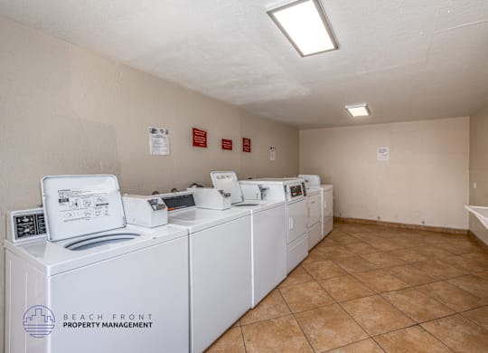 A laundry room with washers and dryers and a sign that says Beach Front Property Management.