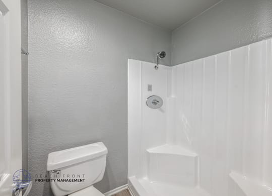 A white bathroom with a toilet, sink, and shower.