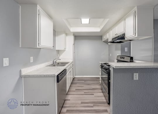 A kitchen with a stove, sink, and cabinets.