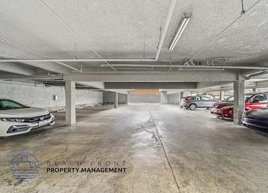 A parking garage with a few cars and a logo for Beach Front Property Management.