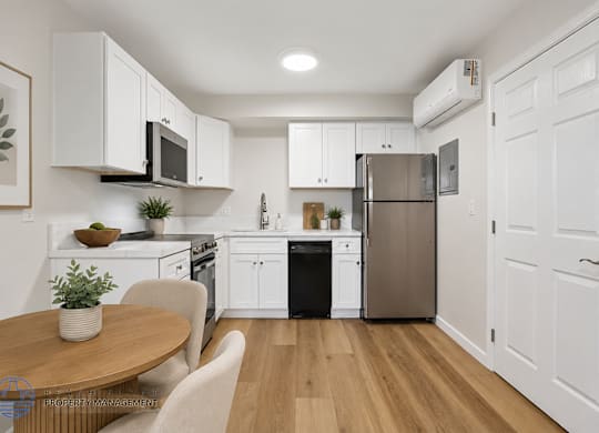 A modern kitchen with wooden floors and white cabinetry.