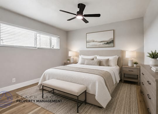 A well-lit bedroom with a large bed, a bench, and a ceiling fan.
