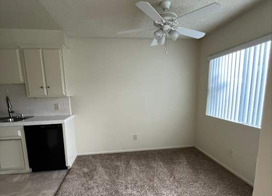 A room with a ceiling fan and a fireplace.