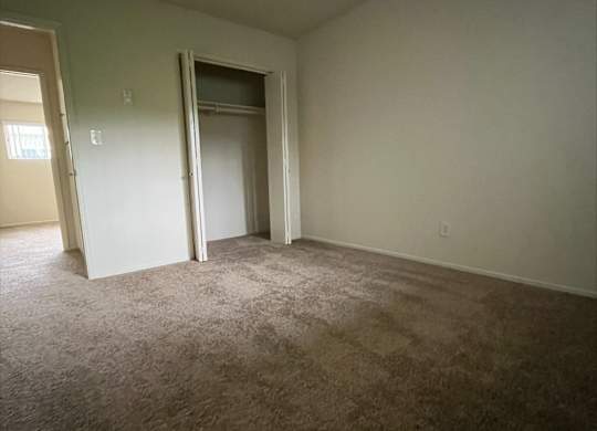 A carpeted room with a door open to another room.