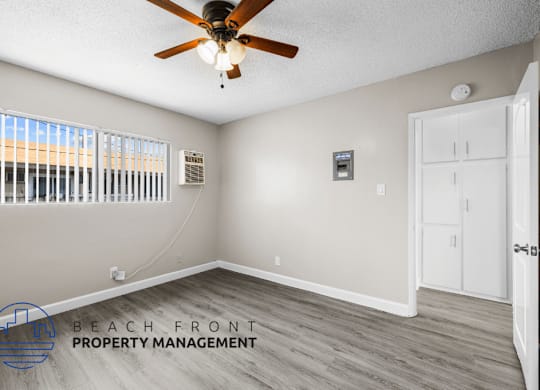 A room with a ceiling fan and a door leading to another room.