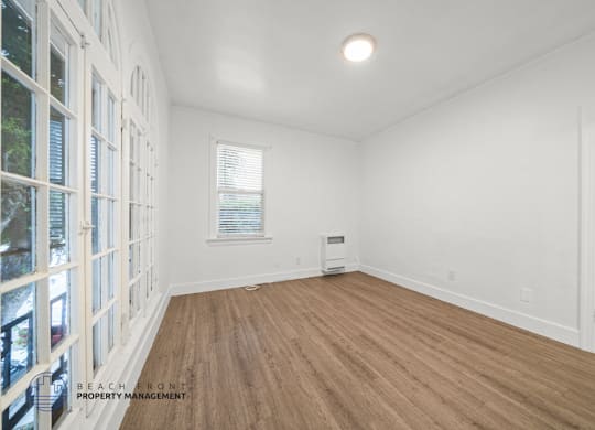 A room with wooden flooring and white walls.