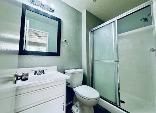 A white bathroom with a toilet, sink, and shower.