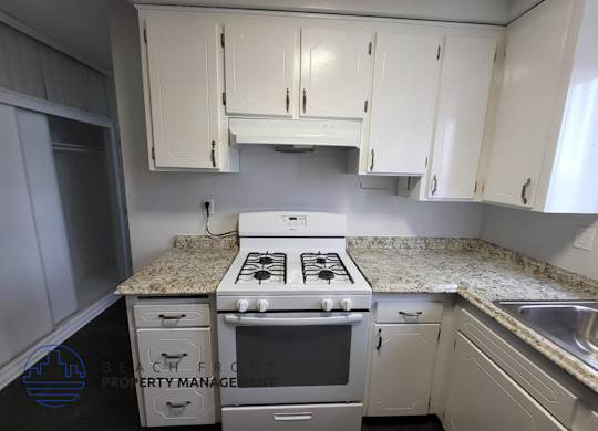 A kitchen with a stove top oven and cabinets.