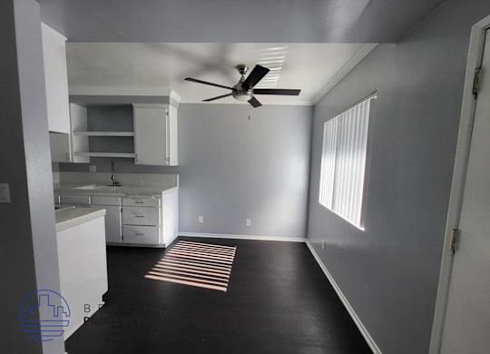 A room with a ceiling fan and a striped rug on the floor.