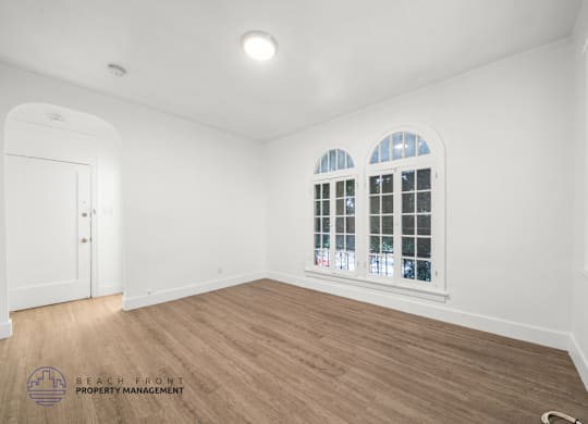A room with wooden flooring and a window with white blinds.
