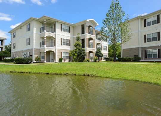 A large apartment complex with a pond in front.