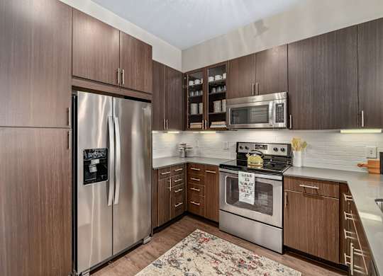 A kitchen with a refrigerator, oven, and microwave.