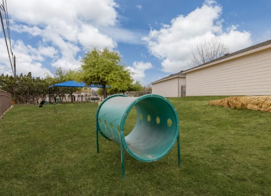 a backyard with a green play area and a green hoop in the grass