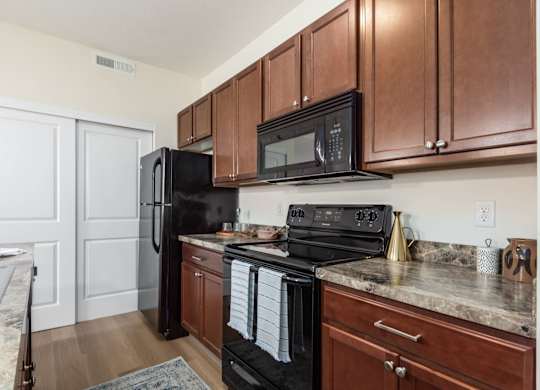 A kitchen with black appliances and wooden cabinets.