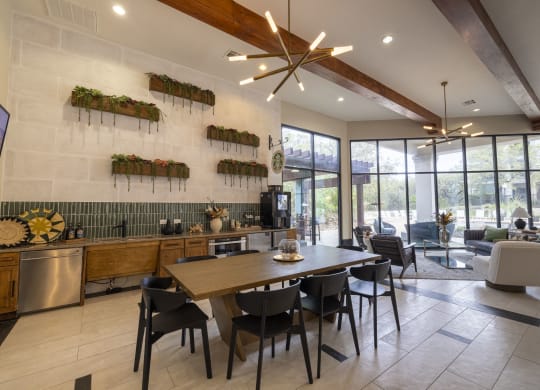 a dining room with a wooden table and chairs and a kitchen with large windows