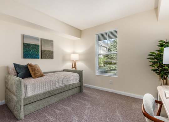A bedroom with a bed, a chair, and a painting on the wall.