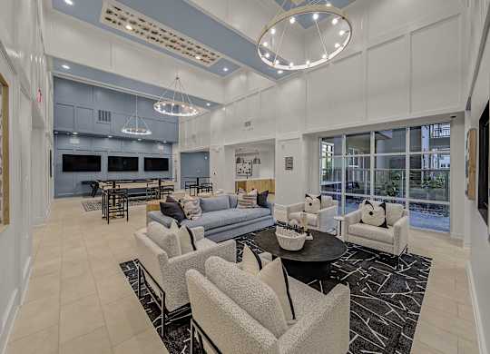 A spacious living room with a black coffee table and grey chairs.