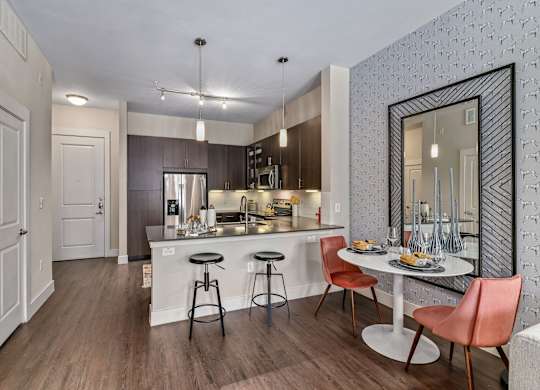 A kitchen with a bar stool and a dining table.