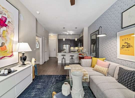 A living room with a grey couch and a painting on the wall.