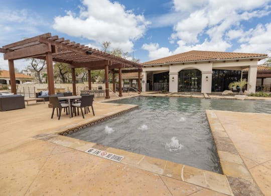 a pool with a patio and a building in the background