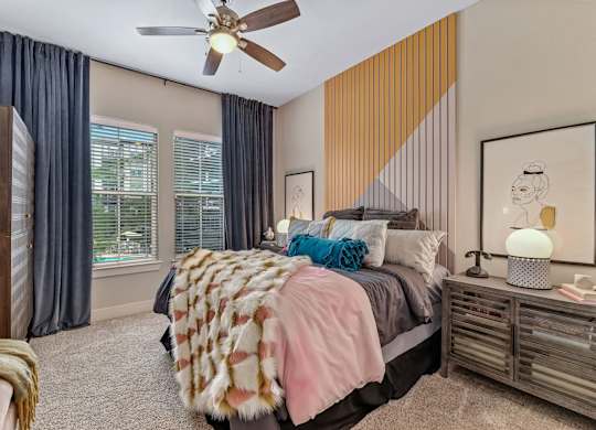 A bedroom with a bed, a ceiling fan, and a window with curtains.