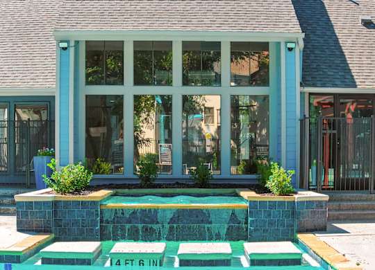 A house with a blue trim and a green fountain in front.