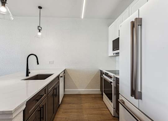 A modern kitchen with a white countertop and dark brown cabinets.