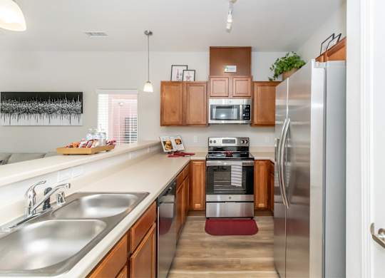 A kitchen with a refrigerator, sink, and microwave.