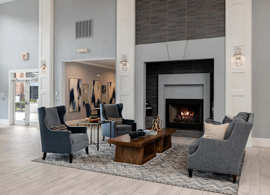 A living room with a fireplace and grey chairs.