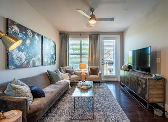 A living room with a brown couch, a glass coffee table, and a television on a wooden cabinet.