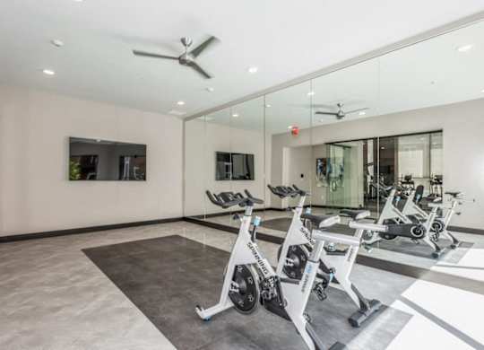 A gym with a mirrored wall and a fan.