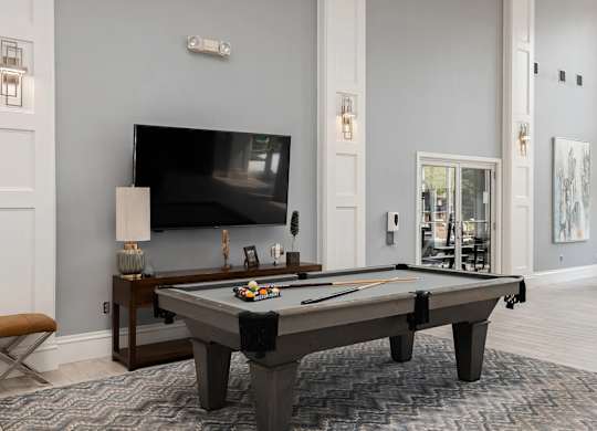A pool table with a television in the background.
