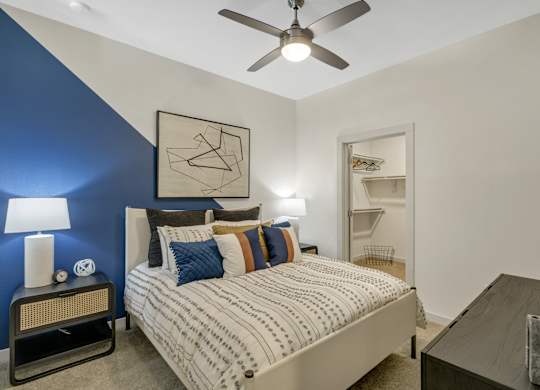 A bedroom with a bed, nightstand, and a ceiling fan.