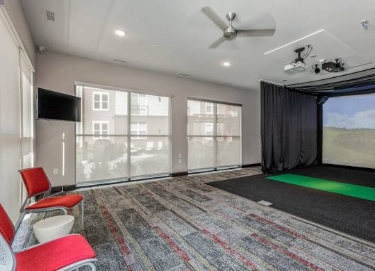 A room with a carpet, a fan, a screen and a chair.