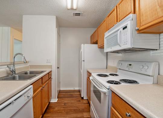 A kitchen with white appliances and wooden cabinets.