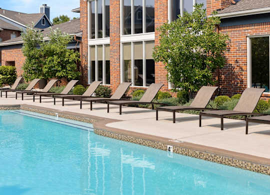A row of lounge chairs are set up on the side of a pool.