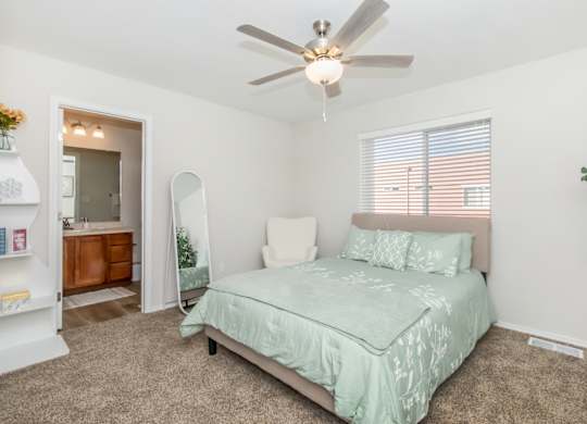 A bedroom with a bed, a ceiling fan, and a window with blinds.