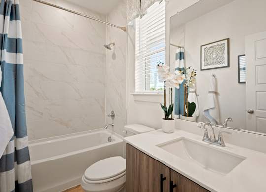 A bathroom with a white sink, toilet, and a shower with a striped shower curtain.