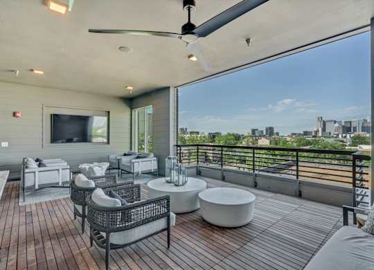 A patio with a ceiling fan and a view of the city.
